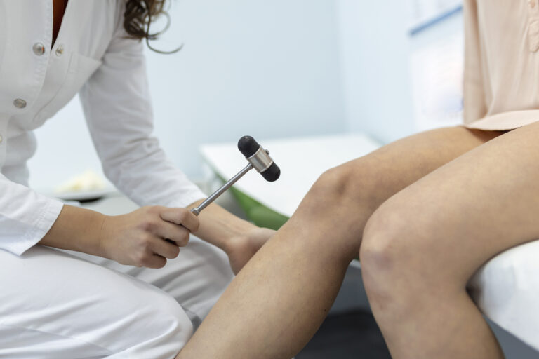 doctor neurologist knocking on knee of patient with hammer in clinic closeup. diagnosis of neurological pathology of knee reflex concept